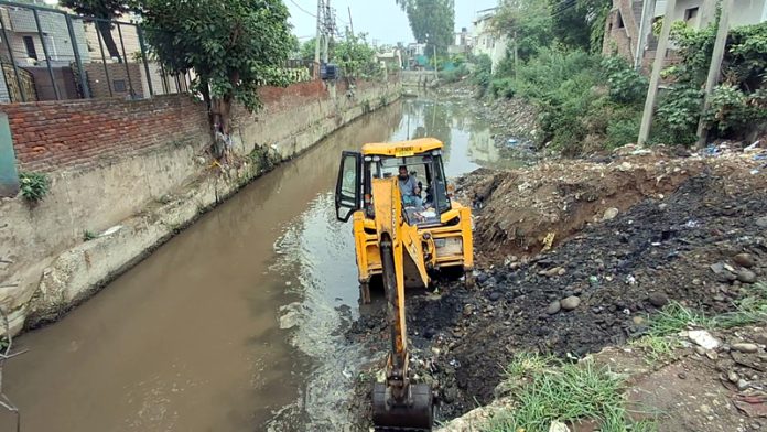 A JCB desilting a nallah at Nanak Nagar, Jammu on Friday.